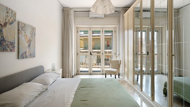 Un dormitorio con cama, una silla, un ventanal y vistas al exterior.