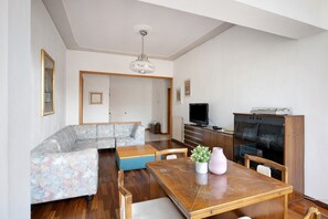 A living room with a sofa, a dining table, and a television. - Apartment 'Casa Elena' with Sea View, Wi-Fi and Air Conditioning (Salerno)