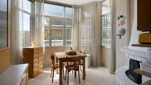 Una habitación de esquina con una mesa de madera, sillas, un armario y una chimenea.