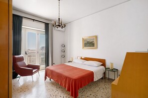 Une chambre d’hôtel avec un lit, une chaise, une table de chevet, une lampe, un tableau au mur et une vue sur la ville par la fenêtre.