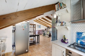 Una cucina con frigorifero in acciaio inossidabile, piano cottura a gas e zona pranzo con tavolo e sedie.