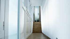 A modern interior with a wooden staircase, glass doors, and a white wall. - Apartment 'Special House' with Wi-Fi and Air Conditioning (Salerno)