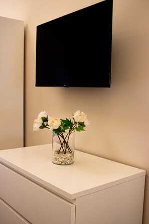 A white cabinet with a vase of white flowers on top.