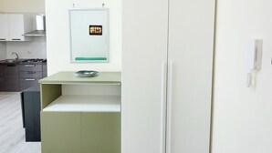 Une cuisine moderne avec un réfrigérateur blanc, un petit îlot central doté d’un évier et un four à micro-ondes fixé au mur.