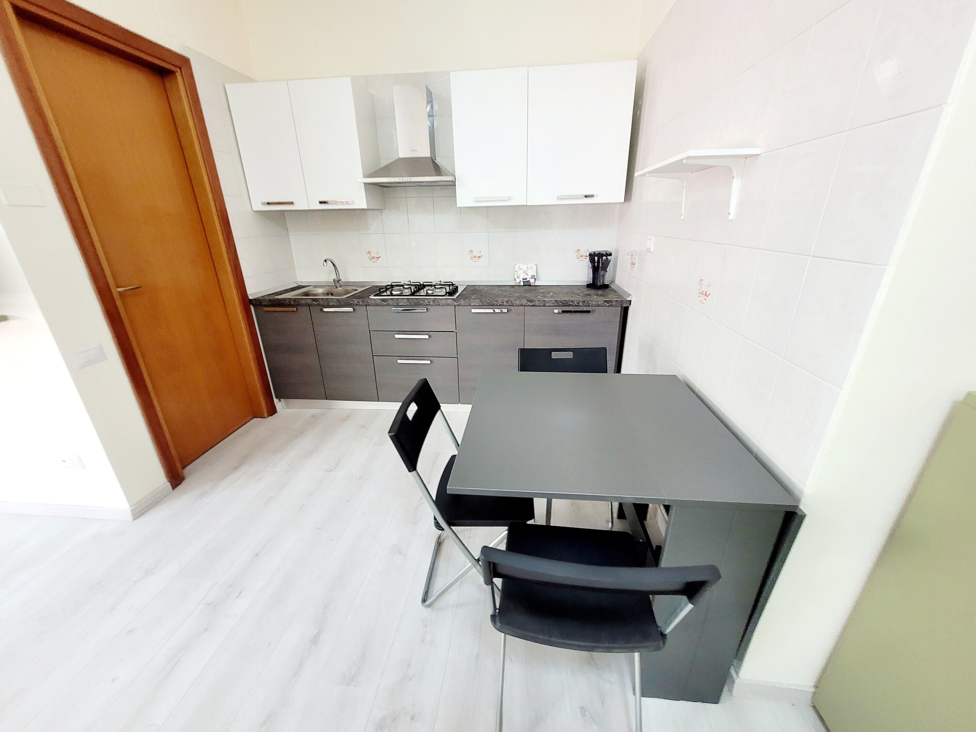 Een kleine keuken met een eettafel, stoelen en een fornuis.