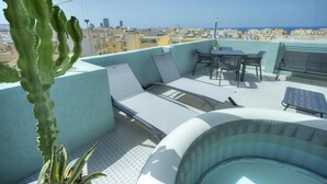 A rooftop terrace with seating, a table, and a hot tub.