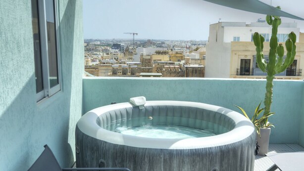 A rooftop terrace with a hot tub, lounge chairs, and a cactus plant.