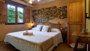 Un dormitorio con pared de piedra, cama de madera y una pequeña mesa con una silla.