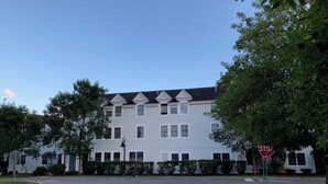 A multi-story building with a symmetrical facade, large windows, and a stop sign at the entrance.