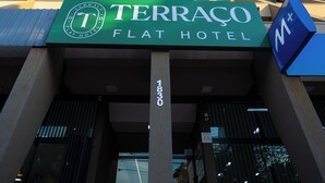 El exterior del Hotel Terraco Flat, con un cartel llamativo, un diseño arquitectónico moderno y un cielo azul despejado al fondo.