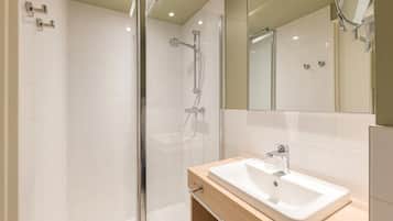 A modern bathroom with a glass-enclosed shower, a wooden vanity with a white sink, and a large mirror.