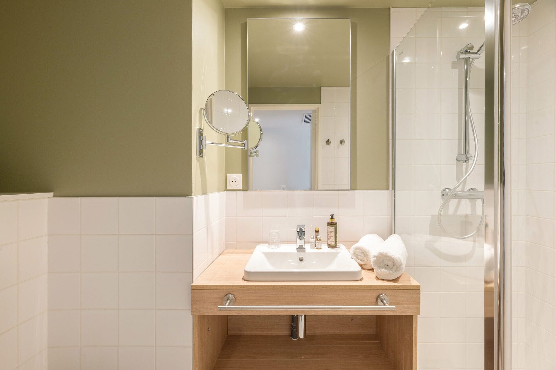 A modern bathroom with a wooden vanity, a mirror, a sink, and a shower.