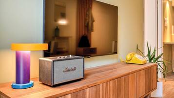 Un salon moderne avec un meuble en bois, un amplificateur Marshall vintage et un téléphone à cadran jaune.