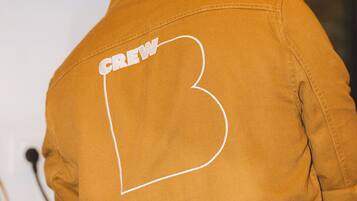 Una persona con una chaqueta que lleva la palabra 'CREW' y una gran letra 'B' en la espalda.