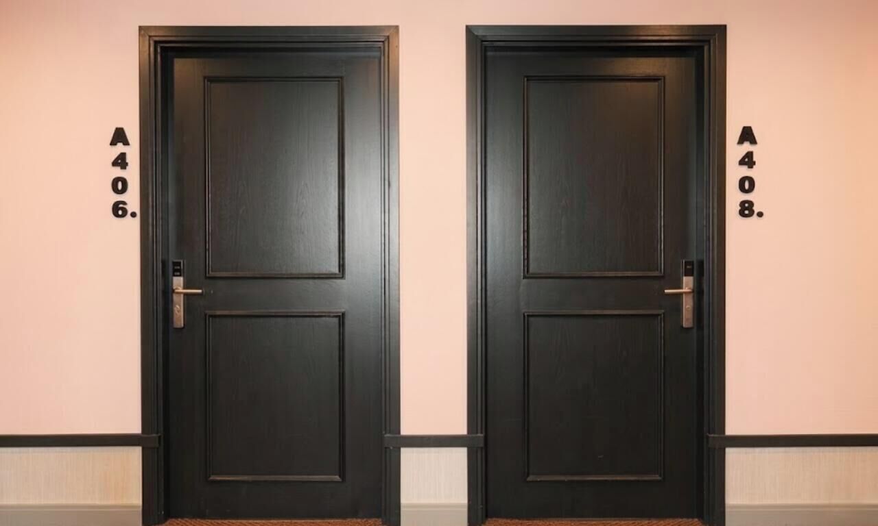 Deux portes identiques de couleur sombre, chacune étant munie d’une étiquette numérique fixée au mur à côté.