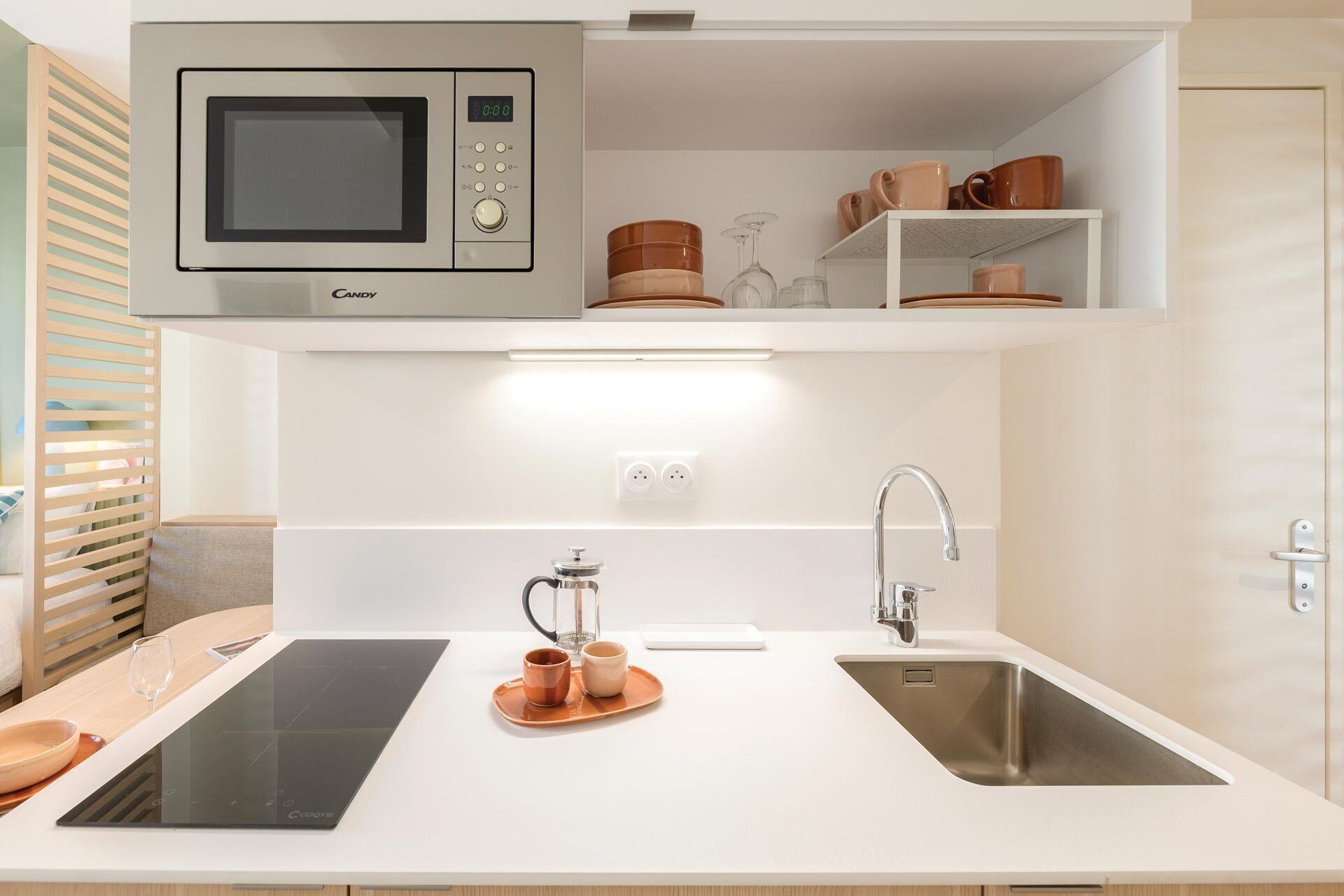 A modern kitchen with a built-in microwave, a sink, and a coffee maker.