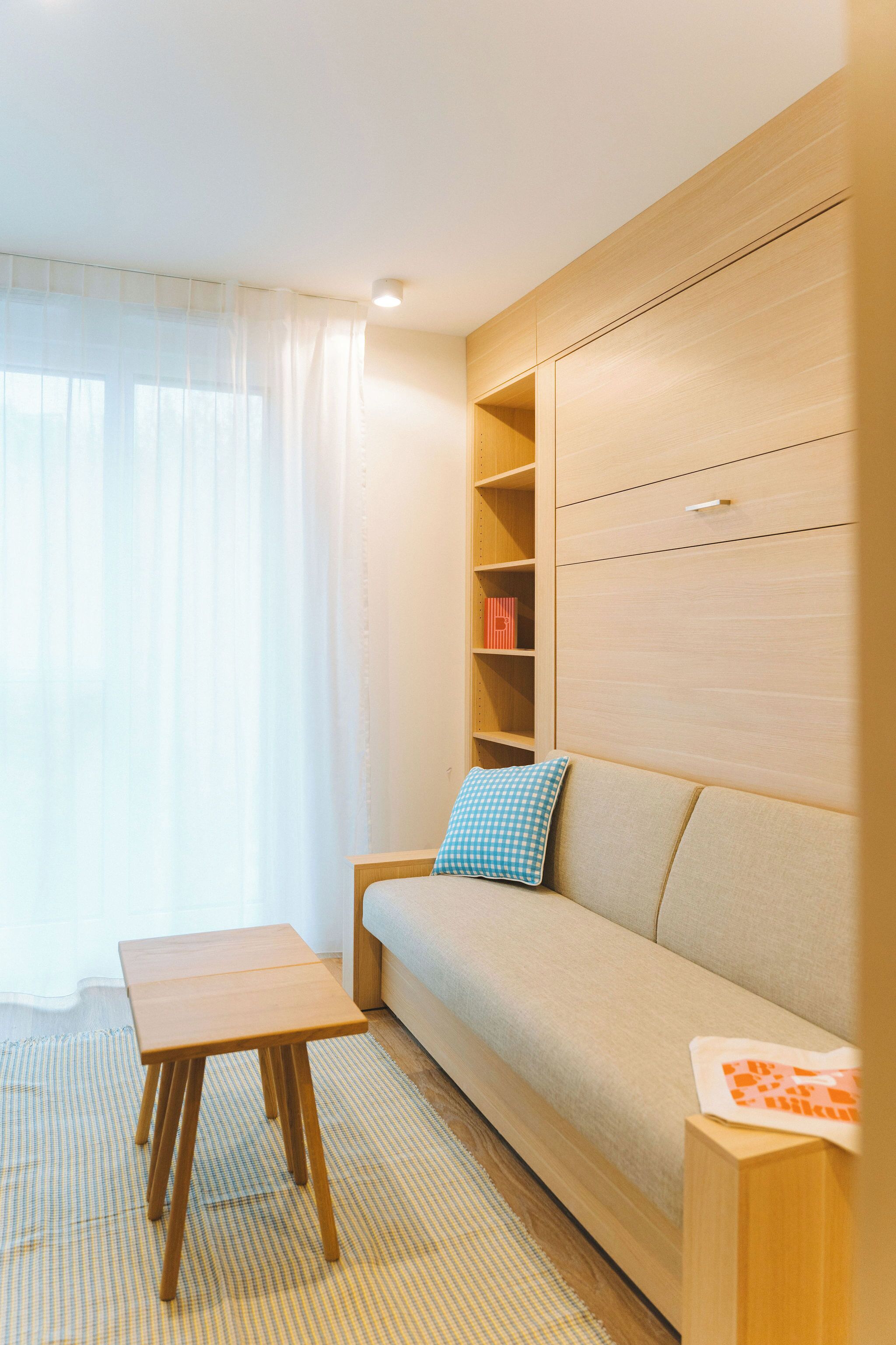 Una sala de estar moderna con un sofá, una mesita de madera y estanterías empotradas.