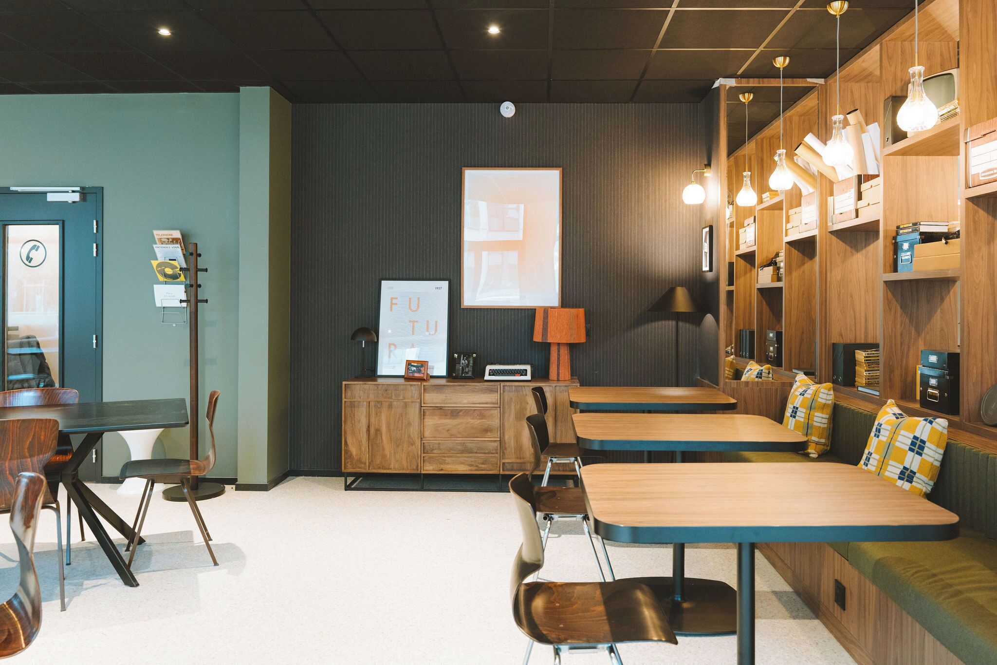 En moderne café med træborde og stole, en disk med menu og en vægmonteret lampe.
