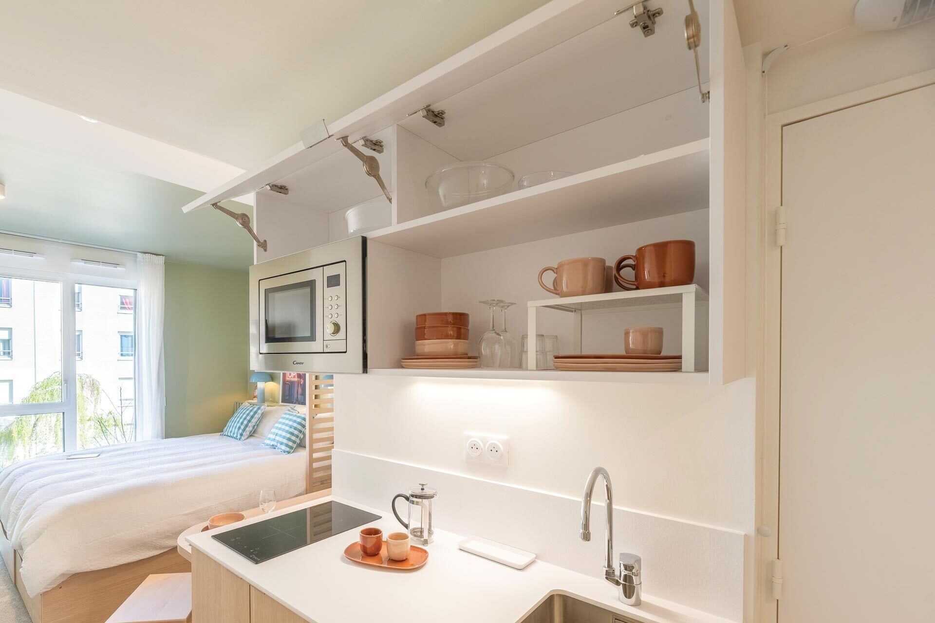 A compact kitchen with a microwave, coffee maker, and sink.