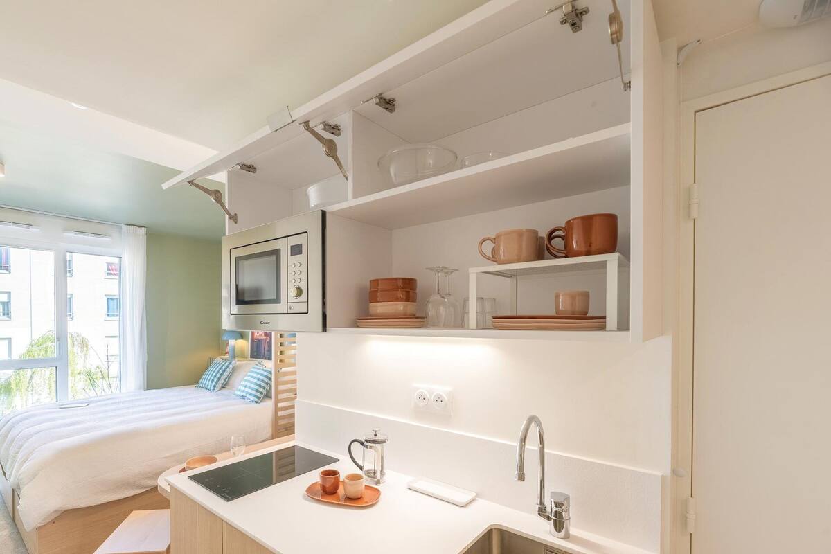 Una cocina compacta equipada con microondas, cafetera y lavamanos.