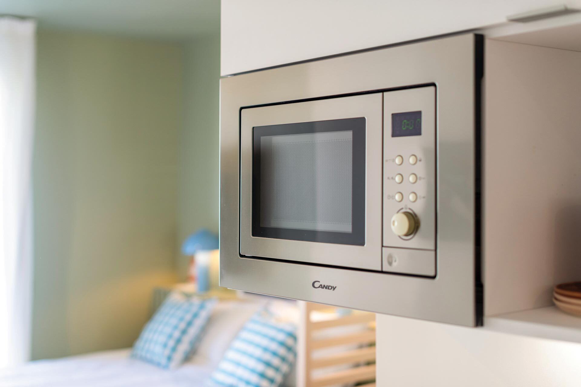 Un microondas moderno con pantalla digital y botones de control, instalado en una pared de una habitación de hotel.