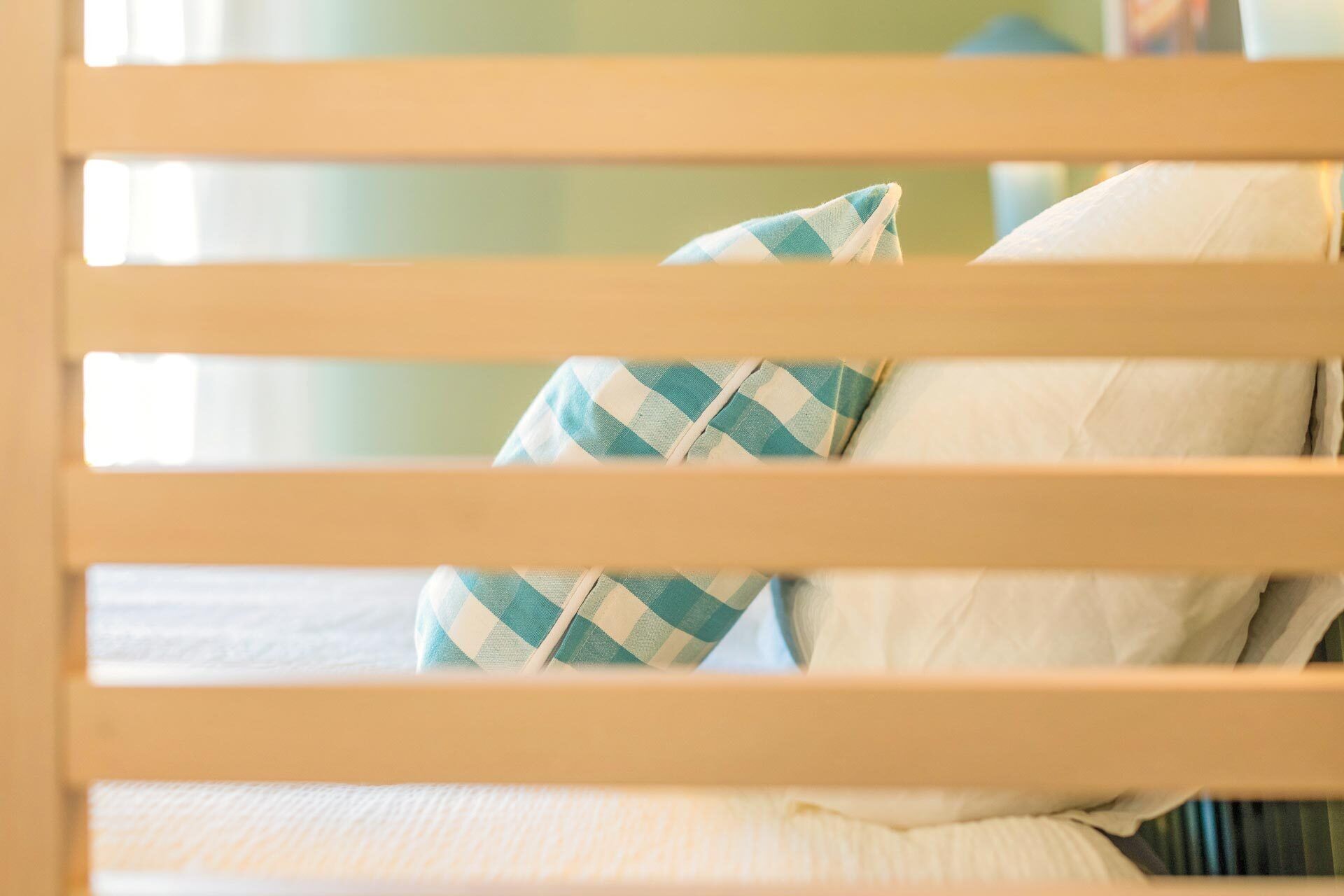 A bed with white bedding and a checkered pillow.