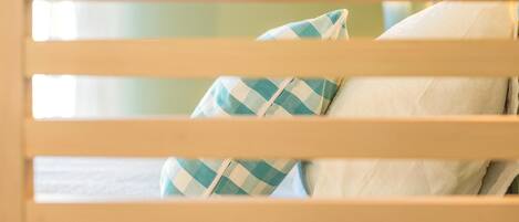 A bed with white bedding and a checkered pillow.