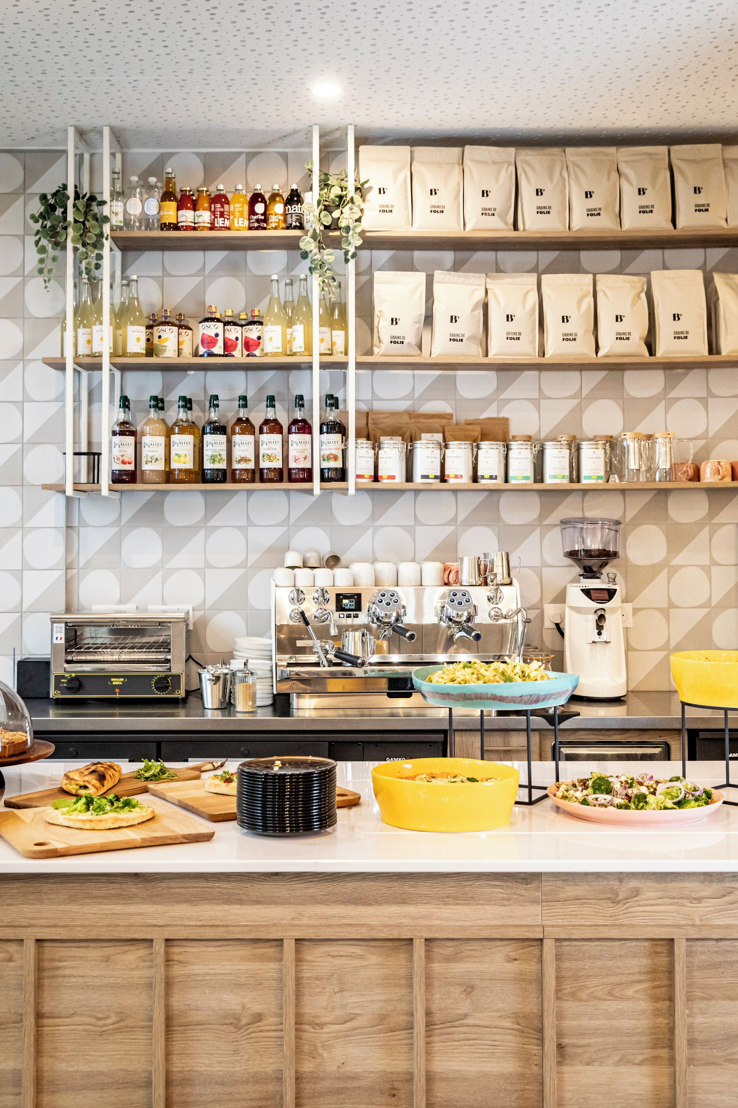 Un área de cocina con estantes llenos de diferentes alimentos, una máquina de café y una encimera con estaciones de preparación.