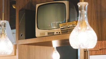 Una estantería de madera con un televisor antiguo, libros y una lámpara.