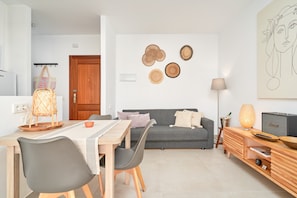 Un salon moderne comprenant un coin repas, un canapé gris, un buffet en bois et des œuvres d’art murales.