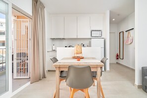 Un appartement moderne comprenant un coin repas, une cuisine et un balcon avec une porte-grille.