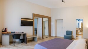A modern hotel room with a bed, desk, chair, and a small kitchenette. - Rooftop Parthenopeo - Contemporary Rooms (Naples)