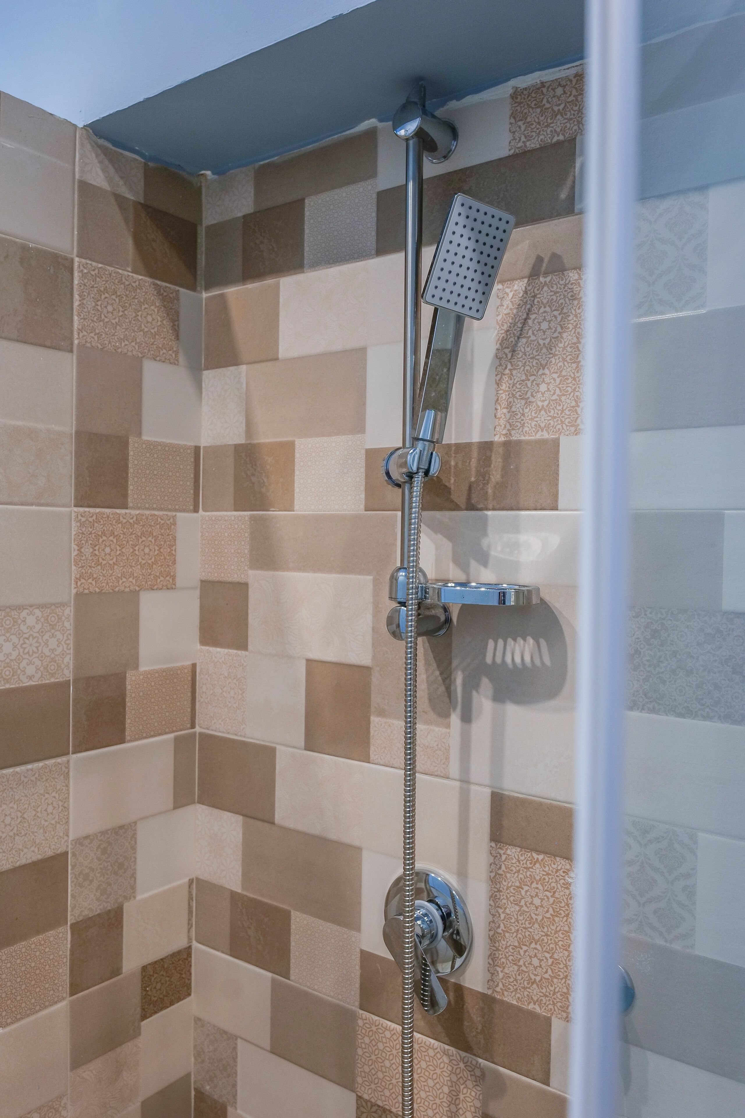 A shower with a handheld showerhead and a wall-mounted control valve.