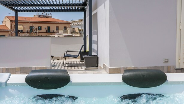 A rooftop pool with two hot tubs, a pergola, and a view of buildings in the background. - Rooftop Parthenopeo - Contemporary Rooms (Naples)