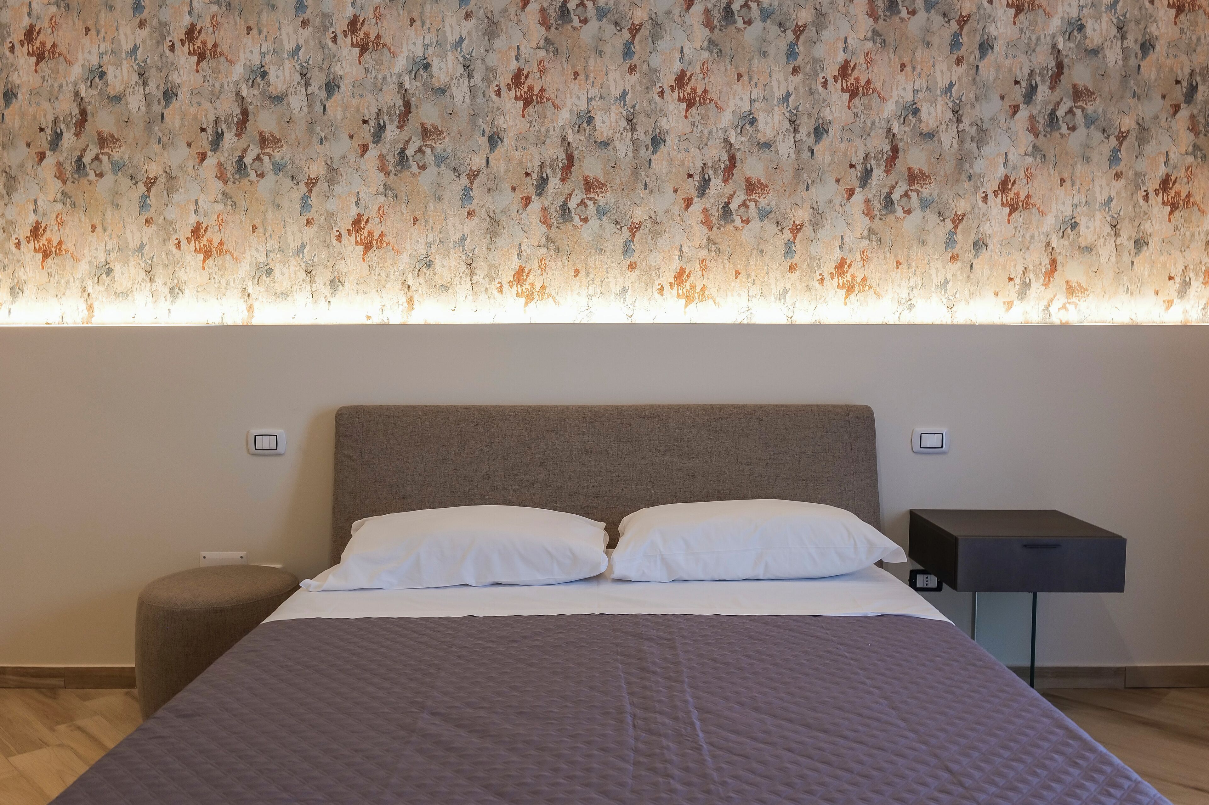 Een moderne hotelkamer met een groot bed, een nachtkastje en een wandlamp.