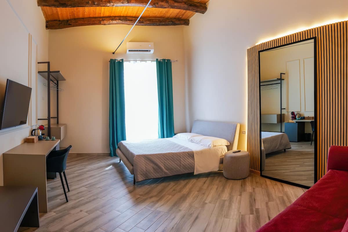 Un dormitorio moderno con techo de madera, una cama, un escritorio y un espejo grande.