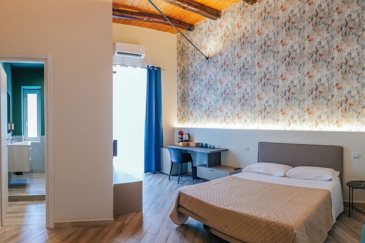 Habitación de hotel con cama, escritorio y zona de ducha.
