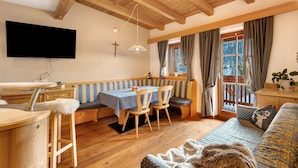 A wooden interior with a dining area, a sofa, and a TV mounted on the wall.