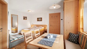 A compact room with a bed, a sofa, a dining table, and a wooden wardrobe. - Studio Apartment 'Apartment Ramei' with Mountain View, Shared Garden and Wi-Fi (La Valle)
