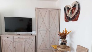 A living room with a TV, wooden cabinets, wicker chairs, and a decorative wall piece.