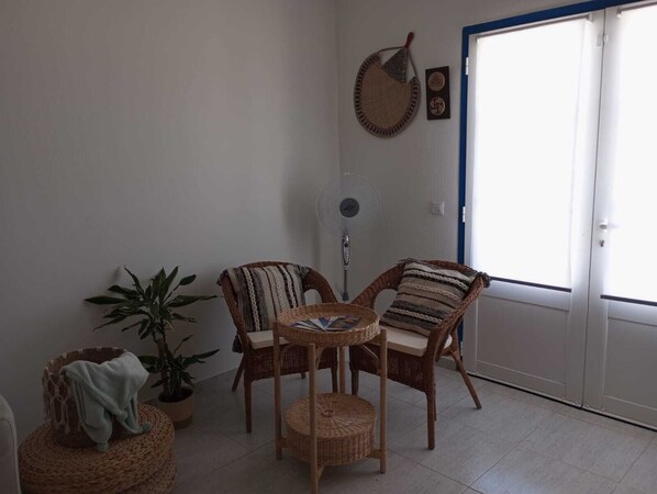 A cozy room with wicker furniture, a fan, and a potted plant.