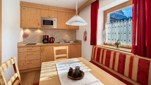 Una cocina compacta con armarios de madera, un microondas y un comedor con mesa y sillas.