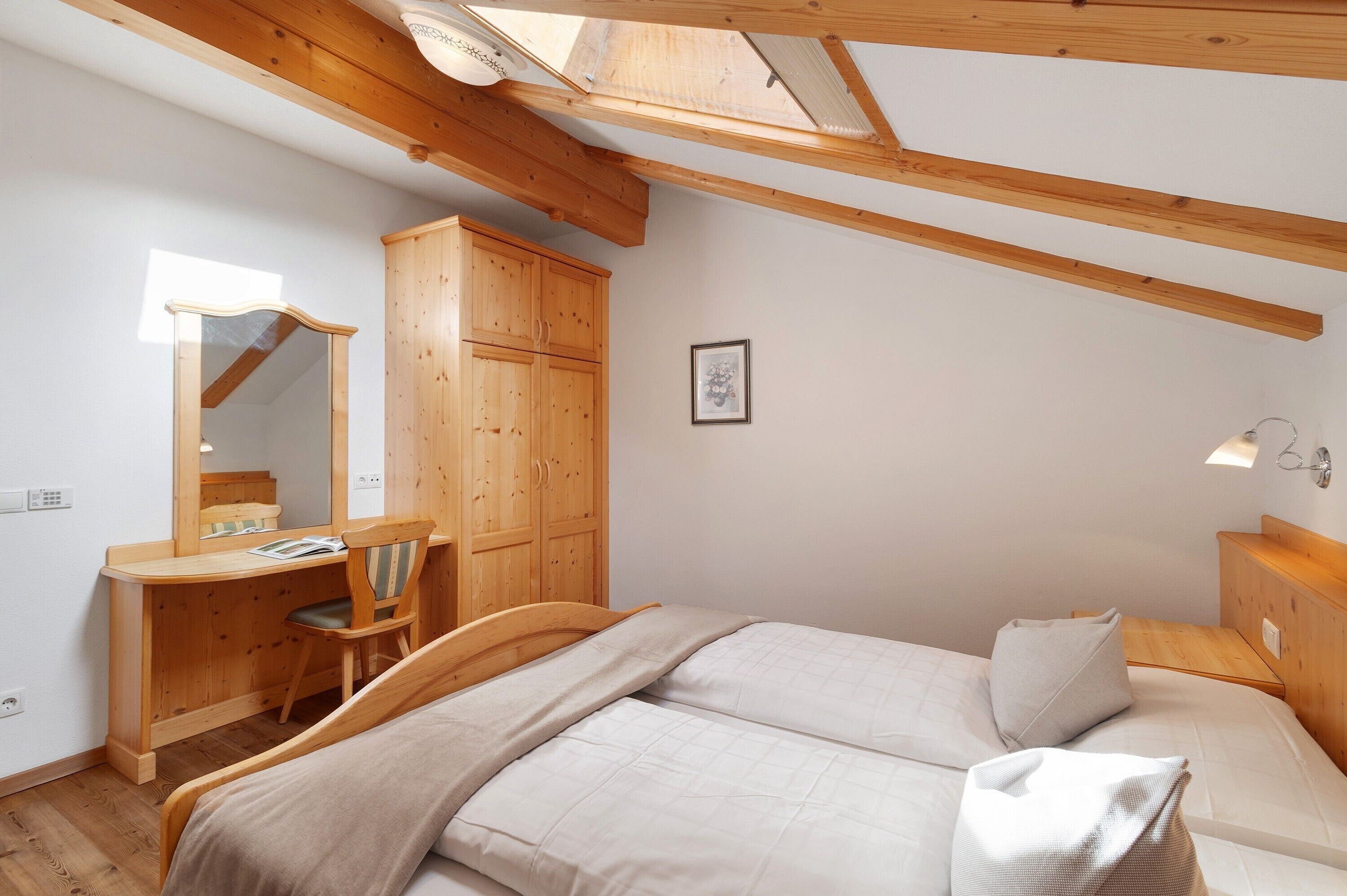 Una camera da letto con una scrivania in legno, una sedia e un letto.