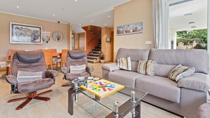 A modern living room with a sofa, two armchairs, a coffee table with a board game, a staircase, and a dining area. - Country House 'Casa La Manzana' with Mountain View, Private Terrace and Wi-Fi (Villaviciosa)