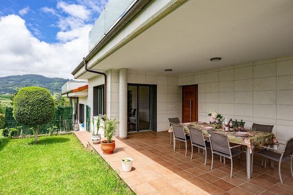 Un patio con una mesa de comedor dispuesta para cuatro personas, rodeada de sillas, y vista a las montañas al fondo.