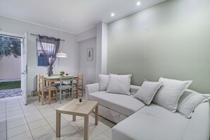 A modern living room with a sofa, a small table, and a dining area with chairs. - Studio Apartment 'Elaia  5' with Mountain View, Wi-Fi and Air Conditioning (?e???da)