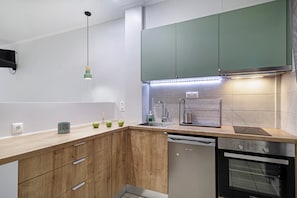 Una cocina moderna con armarios de madera, lavavajillas, horno y una lámpara colgante.