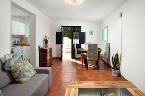 A living room with a sofa, coffee table, and dining area with chairs and a table.
