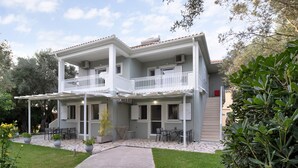 Un edificio de dos pisos con balcón, mobiliario exterior y un patio empedrado.
