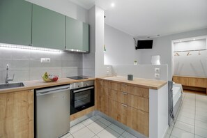 Een koelkast, een oven, een kookplaat, kookgerei, borden en bestek